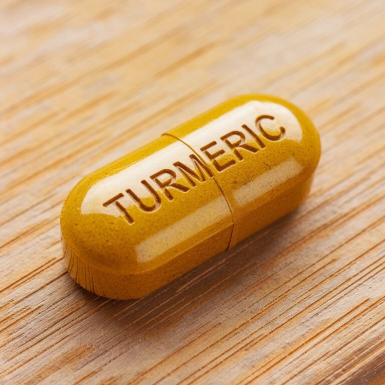 A turmeric (curcumin) supplement pill resting on a wooden table, symbolizing its natural anti-inflammatory and health-boosting properties."